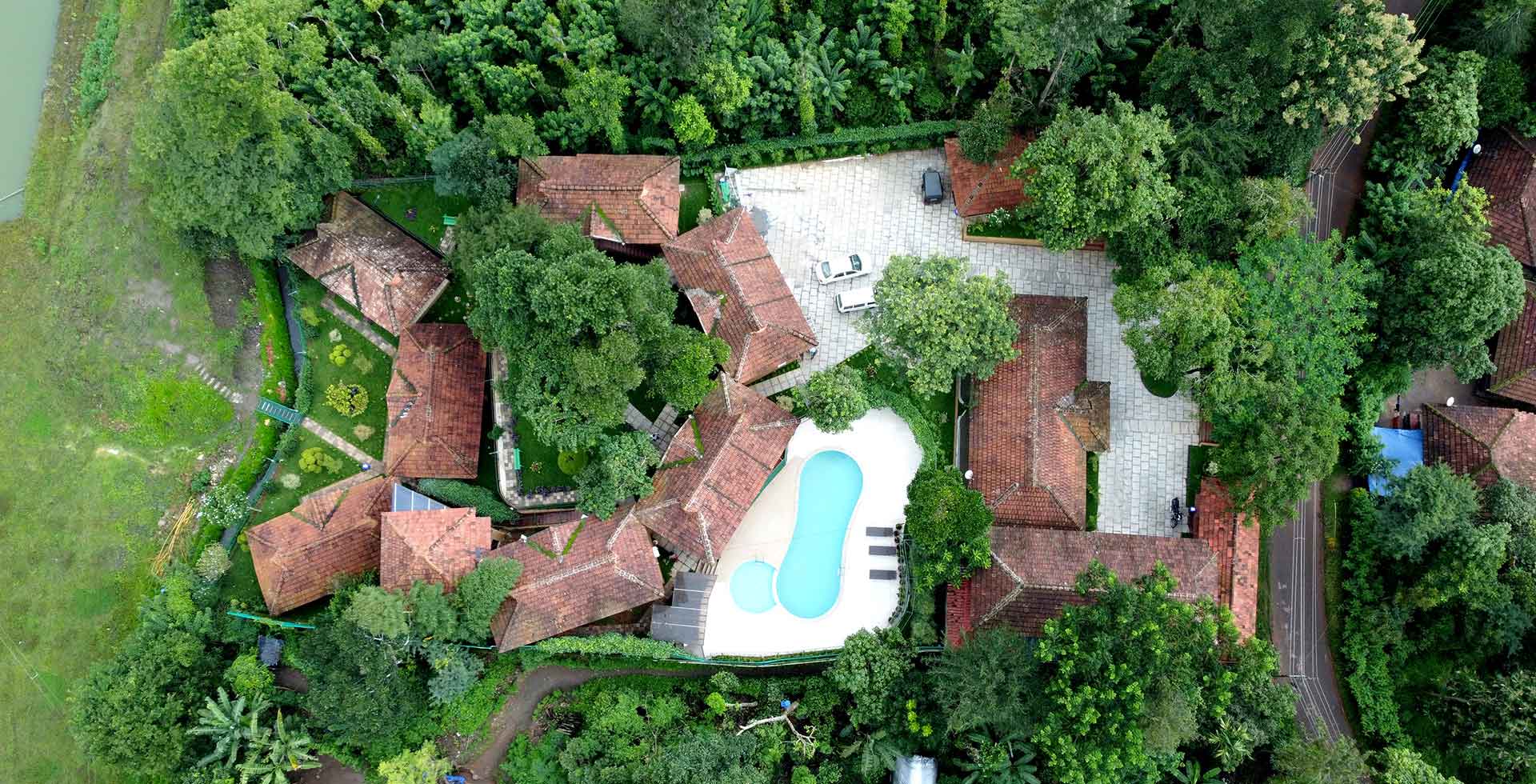 A high-angle view of Mysterymaze resort, showing the pool, cottages, and trees